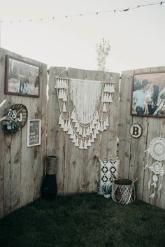 a wooden fence with pictures hanging on it and other items in the yard around it