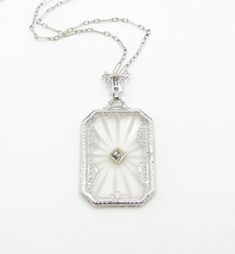 Art Deco/1920s 14k white gold .01 carat natural diamond pendant is .75" x 1.25" 17" original paperclip chain condition: excellent Beautiful Art Deco camphor glass or "boudoir" necklace, crafted of 14 karat white gold and hand engraved rock crystal.  The necklace features a nice sized pendant that measures .75" wide and 1.25" high.  Set at the center is a .01 carat natural diamond, set against a rectangular rock crystal with a hand engraved starburst pattern on the reverse.  This pendant is so lovely! The pendant is framed by openwork filigree, and hangs from its original, 17", 14k gold paperclip chain.  The necklace is in excellent condition, with no damage or discoloration.  It is marked 14k and is guaranteed to be 14k gold.  This gorgeous antique necklace would be perfect as part of a vi Luxury White Gold Art Deco Necklace, Necklace Art Deco, Starburst Pattern, Art Deco 1920s, Necklace Art, Art Deco Necklace, 14k Gold Necklace, Antique Necklace, Diamond Set