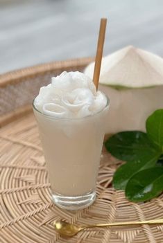 a glass filled with ice cream sitting on top of a wicker tray next to a green leaf