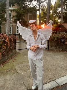 a man dressed as an angel standing on the sidewalk with his hands in his pockets