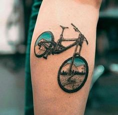 a tattoo on the arm of a person with a mountain bike in front of it