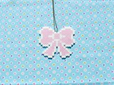 a pink cross stitched butterfly on a blue background with white and green dots,