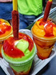 three different colored drinks in plastic cups with straws sticking out of the top one