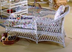 a white wicker day bed sitting on top of a floor next to a basket