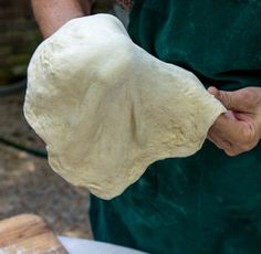 a person in an apron is kneading dough