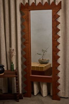 a vase with a plant in it sitting on top of a table next to a mirror