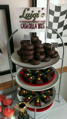 three tiered trays filled with chocolate cupcakes and candy covered donuts