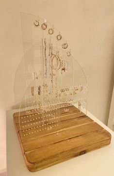 a display case with jewelry on top of a wooden board in front of a white wall