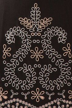 an embroidered design on a black shirt with white and gold details is shown in close up