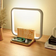 a cell phone sitting on top of a wooden table next to a lamp and some books