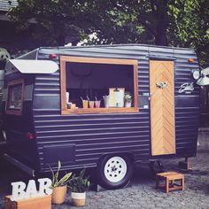 an old camper converted into a bar with potted plants