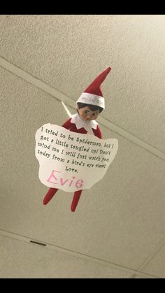 an elf hanging from the ceiling with a sign attached to it's back end