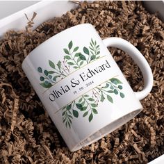 a white coffee mug sitting on top of a pile of wood shavings in a box