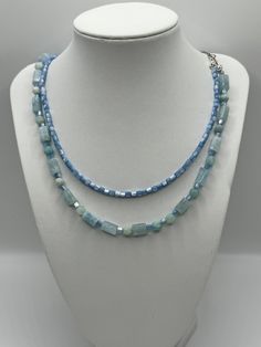 This elegant display a duo of features a serene blue  necklaces, each presenting a unique shape and size of bead, creating a symphony of sky and sea hues.  The first strand (small) features natural shell beads and the  larger cylindrical tube beads are aquamarine . The longest necklace presents a harmonious blend of spherical and tubular beads, lending a dynamic and versatile appearance. Together, they form a layered cascade of tranquil blues, perfect for adding a touch of sophistication and coo Elegant Light Blue Necklace With Beaded Chain, Light Blue Aquamarine Necklace With Gemstone Beads, Light Blue Aquamarine Gemstone Beads Necklace, Adjustable Light Blue Necklaces With Natural Stones, Ocean-inspired Blue Beaded Necklaces With Round Beads, Light Blue Single Strand Jewelry For Jewelry Making, Long Blue Necklace With Polished Beads, Handmade Ocean Color Necklaces For Jewelry Making, Blue Aquamarine Single Strand Jewelry