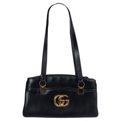 100% authentic Gucci Arli large tote in black calfskin featuring gold-tone hardware. The interior is divided in two compartment with zipper closure and lined in light pink grosgrain fabric with one zipper pocket against the back. The design features a large gold-tone GG on the front, one open pocket on the front and on the back, and adjustable shoulder-straps. Has been carried and shows soft scratches to the front and back. Overall in excellent condition. Comes with dust bag. 2019 Resort Measure Gucci Black Bag, Gucci Leather, Gucci Black, Black Bag, Handle Bag, Large Tote, Fashion Handbags, Shoulder Straps, Design Features