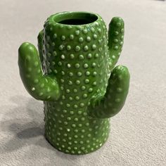 a green cactus shaped vase sitting on top of a table