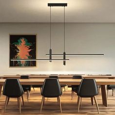 a dining room table with black chairs and an art piece hanging over it's head