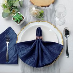 a place setting with napkins, silverware and succulents