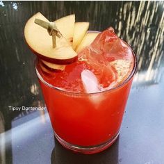 an apple slice is on top of a drink in a glass with ice and water