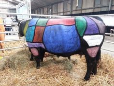 a colorful cow is standing in the hay