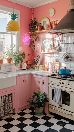 a kitchen with pink walls and black and white checkered flooring, potted plants on the stove