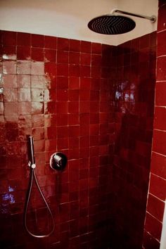 a red tiled shower in a bathroom next to a toilet