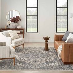 a living room with two couches, chairs and a rug in front of three windows