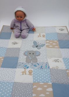 a baby doll sitting on top of a blue and white quilted bed coverlet