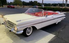 an old white car parked in a parking lot