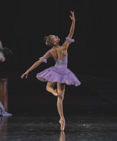 a ballerina in a purple tutu is performing on stage