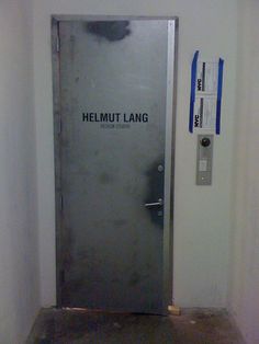 an open door with the words helmmut lang on it in front of a wall