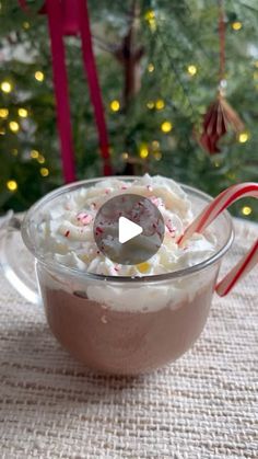 a glass bowl filled with whipped cream and candy canes next to a christmas tree