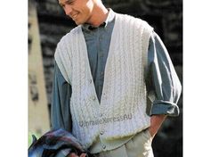 a man wearing a sweater vest and smiling at the camera while holding his jacket over his shoulder