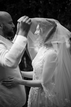 a man and woman standing next to each other in front of a veil on their heads