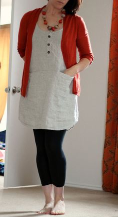 a woman standing in front of a door wearing leggings and a red cardigan