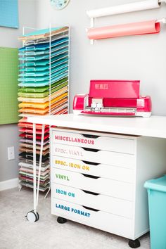 a white desk with lots of different colored papers on it and a sewing machine next to it