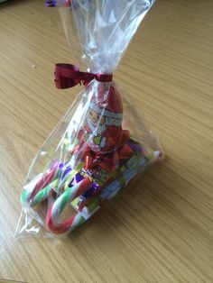 a bag filled with lots of different colored toothbrushes on top of a wooden table