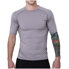 a man with tattoos on his arm wearing a gray shirt and black shorts, standing in front of a white background