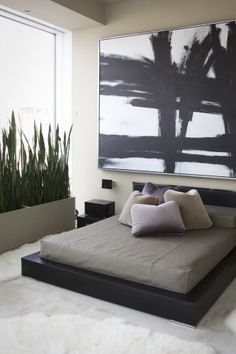 an image of a bed with pillows on it and a plant in the corner next to it