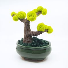 a crocheted bonsai tree sitting in a green pot on a white background