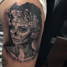 a woman's face with roses and a skull tattoo on her left arm, in black and white