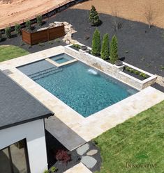 an aerial view of a pool surrounded by grass and trees in the middle of a yard