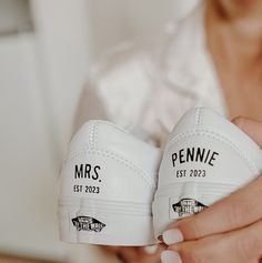 a woman holding two white tennis shoes with the words mrs and mr on them