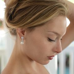 a woman with her hand on her head looking down at the ground while wearing earrings