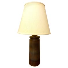 a brown table lamp with a white shade on the base and a light in the middle