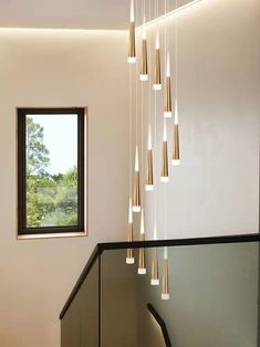 a staircase with lights hanging from the ceiling and a window in the wall next to it