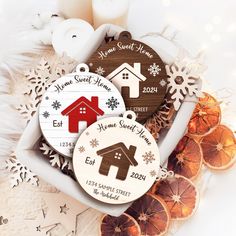 two personalized christmas ornament in a gift box surrounded by oranges and candles