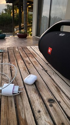 an electronic device is laying on a wooden table outside with other items nearby and in front of the building