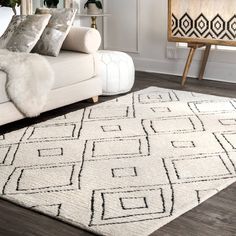 a living room with a white couch and large rug on the floor in front of it