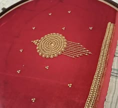 a close up of a red cloth with gold bead work on it and a white background